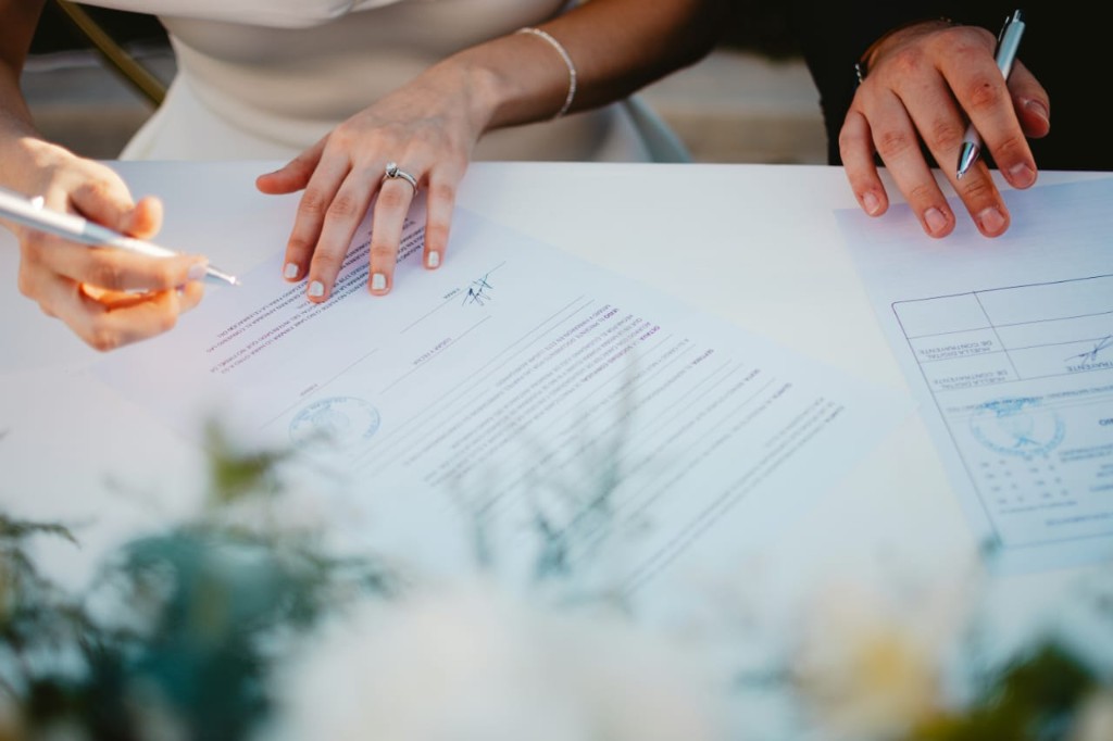 Hands signing official documents with care and guidance
